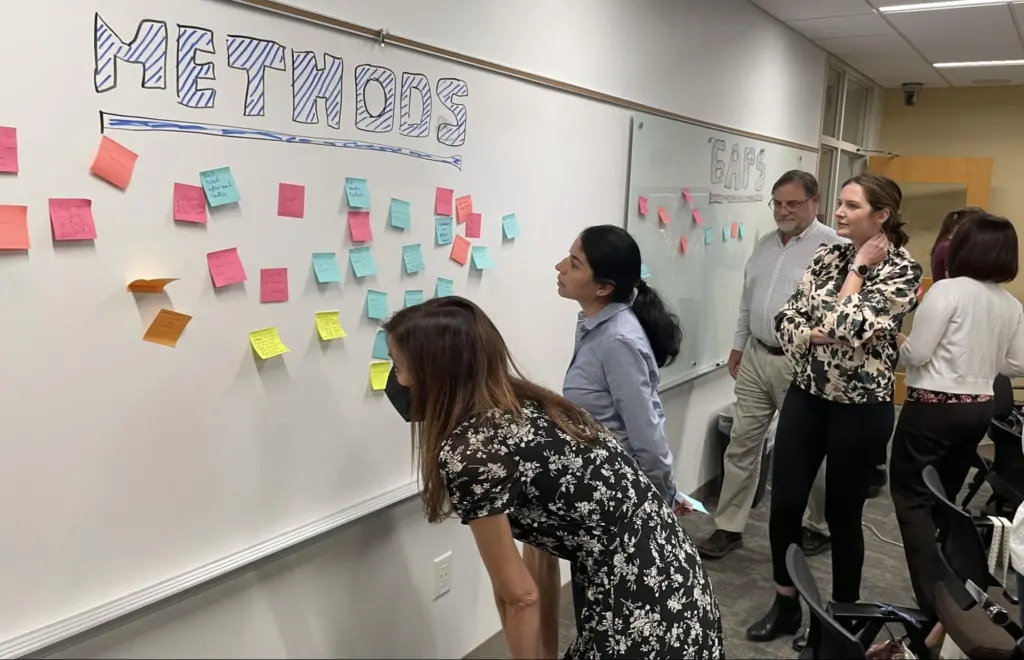 Photo of people reading sticky notes on a whiteboard